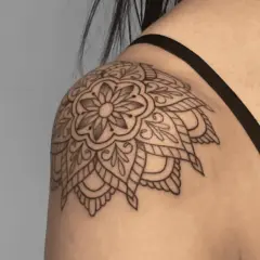 Mandala-Tattoo auf der Schulter einer Frau, detailliert und filigran gezeichnet.
