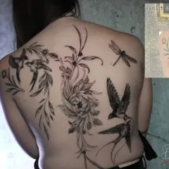 Ein detailliertes Backpiece Tattoo mit Schwalben, einer Libelle und einer großen Blume.
