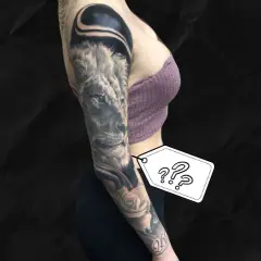 Ein beeindruckendes, all black tattoo ziert den Arm einer Frau. Ein Löwe blickt majestätisch, umgeben von Rosen und abstrakten Formen.