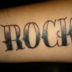 Ein Pickel stört das "ROCK"-Tattoo auf dem Arm.