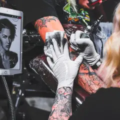 Tätowierer arbeitet an einem Porträt-Tattoo, inspiriert von kreativen Tattoos auf einem Tablet.