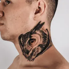 Ein Mann trägt ein detailreiches Eulen-Hals-Tattoo, das wie ein Mandala wirkt.