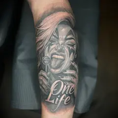 Ein detailreiches Tattoo mit einer Frau, die einen Lolli leckt, und der Aufschrift "One Life". Das Kunstwerk ist in Schwarz und Rot gehalten.