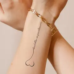 Ein dezentes Tattoo mit den Namen "Charlotte & Jacinta" in geschwungener Schrift, verbunden mit einem kleinen Herz.