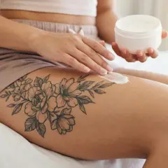 Creme wird auf ein blumiges Tattoo aufgetragen. Die **Folie nach Tattoo**-Pflege ist wichtig für die Heilung.