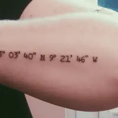 Ein Koordinaten Tattoo in schlichter Schriftart auf dem Oberarm. Die Zahlen markieren einen besonderen Ort.