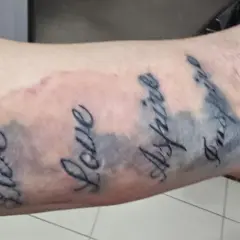 Tattoo mit den Worten "Live", "Love", "Aspire", "Inspire". Die Linien sind etwas unscharf, was auf einen Tattoo Blowout oder eine normale Heilung hindeuten könnte.