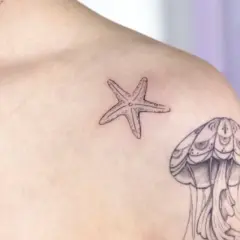 Kleines Seestern-Tattoo auf der Brust, neben einer Qualle.
