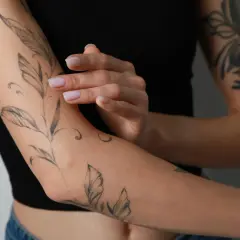 Frauenarm mit Blatt-Tattoo. Das Tattoo schmerzt nach 4 Tagen, die Haut ist leicht gerötet.