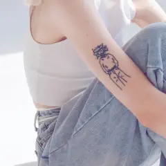 Ein Arm mit einem abstrakten Tattoo, das eine Figur mit Krone zeigt. Ein Beispiel für beste Tattoos, die Persönlichkeit ausdrücken.