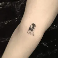 Ein kleines Tattoo auf dem Arm eines Mannes zeigt eine Tür mit Stufen, die zu einem Planeten führt.