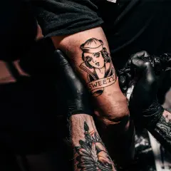 Ein Tätowierer vervollständigt ein "second skin tattoo" einer Frau mit dem Schriftzug "SWEETY" auf einem Arm.