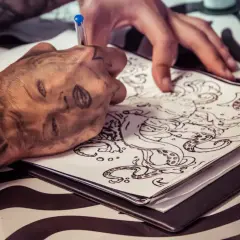 Ein Tätowierer entwirft eine Tintenfisch-Vorlage. Die Frage, wie lange dauert ein kleines Tattoo, hängt von der Komplexität ab.