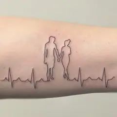 Ein Fineline Tattoo zeigt ein Paar, das Händchen hält, über einer EKG-Linie. Ein schönes Vorher-Nachher-Beispiel für zarte Linienkunst.