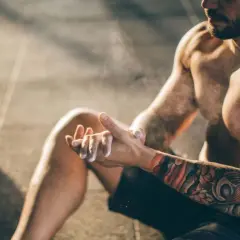 Mann mit beeindruckendem Tattoo auf Brust und Arm, der sich für das Training vorbereitet.