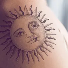 Ein detailreiches Tattoo einer Sonne mit menschlichem Gesicht und Strahlen auf der Haut. Dieses sonnenstrahlen tattoo strahlt Wärme aus.