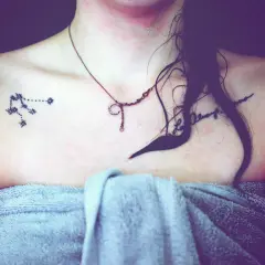 Tattoo eines Sternbilds auf der Schulter einer Frau mit einer Kette und einem Handtuch.