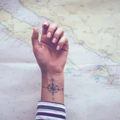 Ein feminines Kompass-Tattoo auf dem Handgelenk, bereit für das nächste Abenteuer auf der Seekarte.