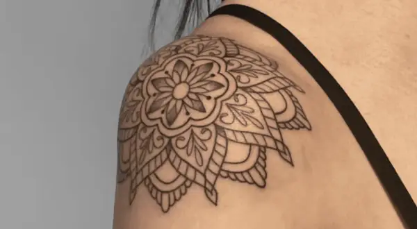 Mandala-Tattoo auf der Schulter einer Frau, detailliert und filigran gezeichnet.