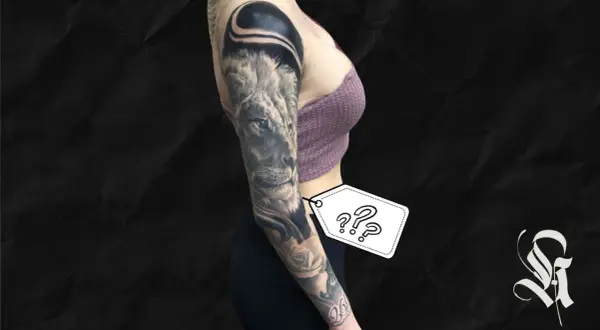 Ein beeindruckendes, all black tattoo ziert den Arm einer Frau. Ein Löwe blickt majestätisch, umgeben von Rosen und abstrakten Formen.