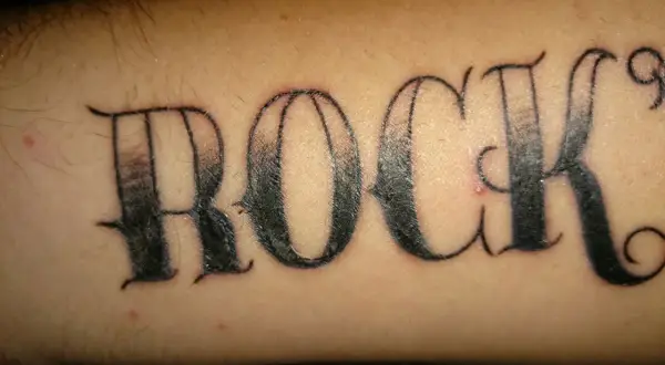 Ein Pickel stört das "ROCK"-Tattoo auf dem Arm.