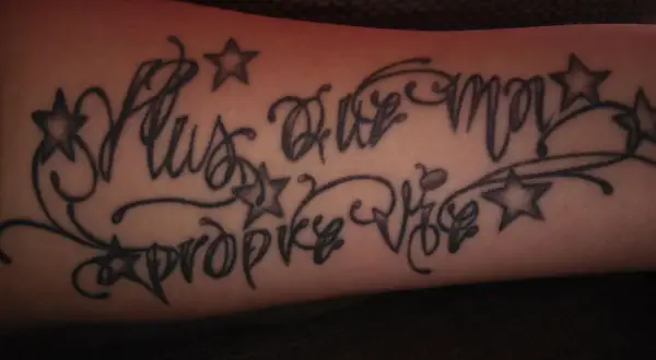 Dezentes Tattoo mit Kindesnamen für einen Mann, verziert mit Sternen und Schnörkeln.