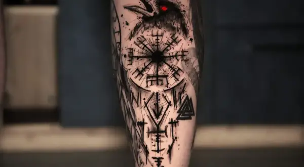 Ein Rabe mit roten Augen blickt auf ein Vegvisir und Runen. Ein Meisterwerk, das verschiedene tattoo stile mischen lässt.