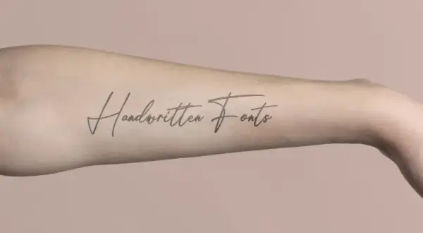 Ein langgezogenes Schrift Tattoo mit dem Schriftzug "Handwritten Fonts" auf einem Arm.