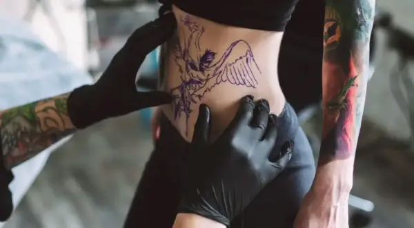 Tätowierer bereitet Motiv vor. Nach dem Stechen ist die Frage: wie lange tattoo mit Bepanthen eincremen?