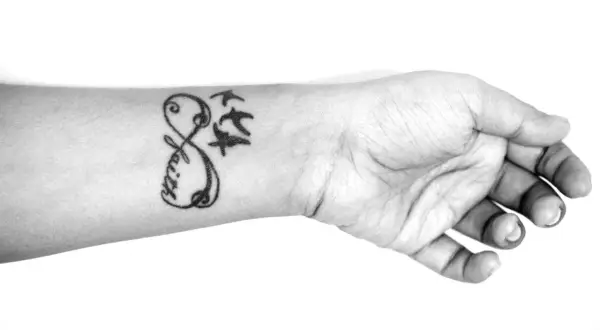 Ein beliebtes Tattoo für Frauen: Ein Unendlichkeitszeichen mit dem Wort "Faith" und drei fliegenden Vögeln auf dem Handgelenk.