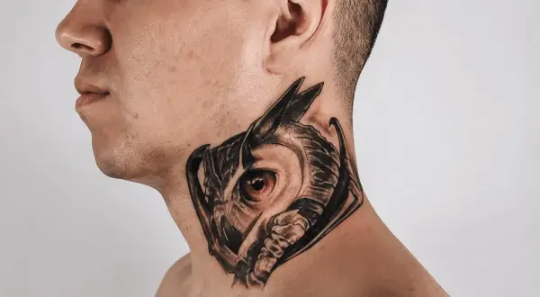 Ein Mann trägt ein detailreiches Eulen-Hals-Tattoo, das wie ein Mandala wirkt.
