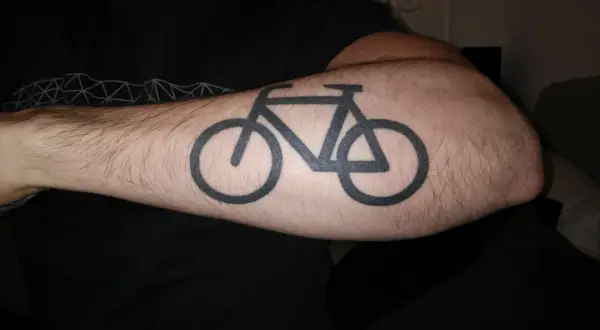 Schwarzes Fahrrad-Tattoo auf einem behaarten Arm. Ein Symbol für die Liebe zum Radfahren nach dem Tattoo.