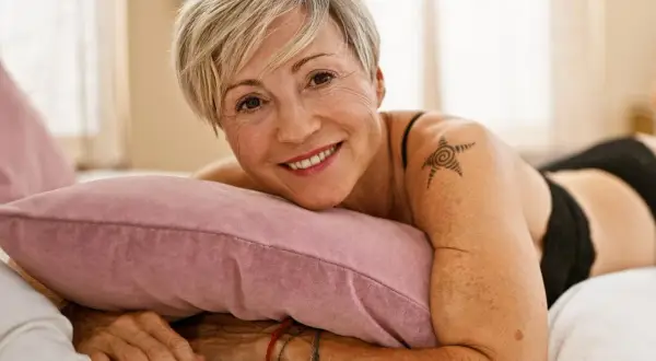 Lächelnde Frau mit kurzem blonden Haar und einem Stern-Tattoo auf der Schulter, das zeigt, dass Tattoos im Alter zeitlos sind.