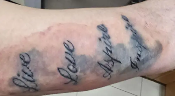 Tattoo mit den Worten "Live", "Love", "Aspire", "Inspire". Die Linien sind etwas unscharf, was auf einen Tattoo Blowout oder eine normale Heilung hindeuten könnte.