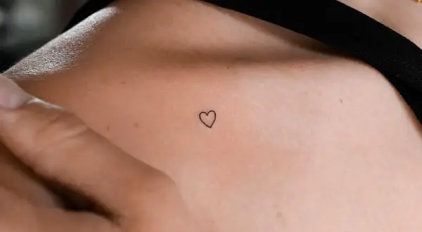Kleines Herz-Freundschaftstattoo auf der Schulter einer Frau, ein zartes Symbol ewiger Verbundenheit.