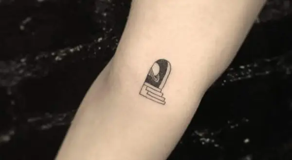 Ein kleines Tattoo auf dem Arm eines Mannes zeigt eine Tür mit Stufen, die zu einem Planeten führt.