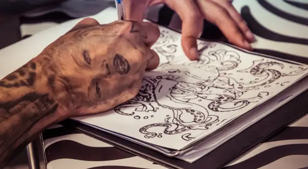 Ein Tätowierer entwirft eine Tintenfisch-Vorlage. Die Frage, wie lange dauert ein kleines Tattoo, hängt von der Komplexität ab.