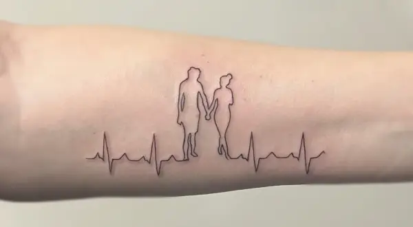 Ein Fineline Tattoo zeigt ein Paar, das Händchen hält, über einer EKG-Linie. Ein schönes Vorher-Nachher-Beispiel für zarte Linienkunst.