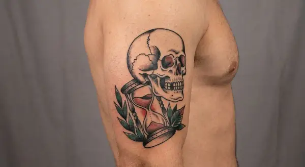 Ein Tattoo mit einem Totenkopf und einer Sanduhr, ein Symbol für die Vergänglichkeit des Lebens.