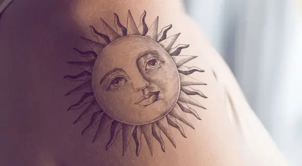 Ein detailreiches Tattoo einer Sonne mit menschlichem Gesicht und Strahlen auf der Haut. Dieses sonnenstrahlen tattoo strahlt Wärme aus.
