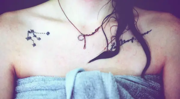 Tattoo eines Sternbilds auf der Schulter einer Frau mit einer Kette und einem Handtuch.