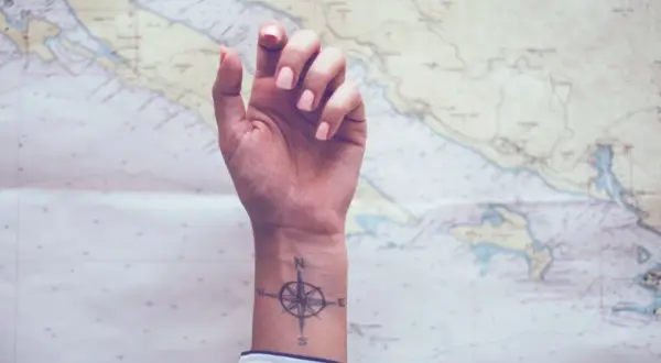 Ein feminines Kompass-Tattoo auf dem Handgelenk, bereit für das nächste Abenteuer auf der Seekarte.