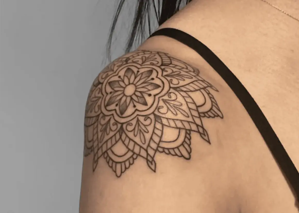 Mandala-Tattoo auf der Schulter einer Frau, detailliert und filigran gezeichnet.