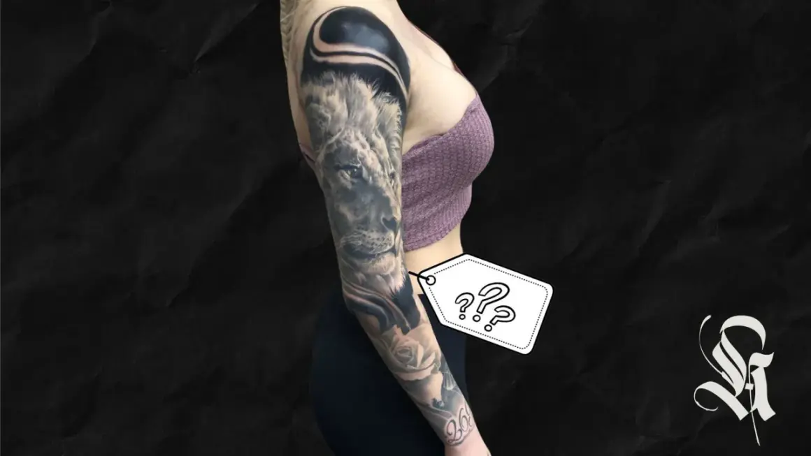 Ein beeindruckendes, all black tattoo ziert den Arm einer Frau. Ein Löwe blickt majestätisch, umgeben von Rosen und abstrakten Formen.