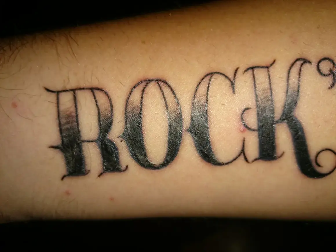 Ein Pickel stört das "ROCK"-Tattoo auf dem Arm.