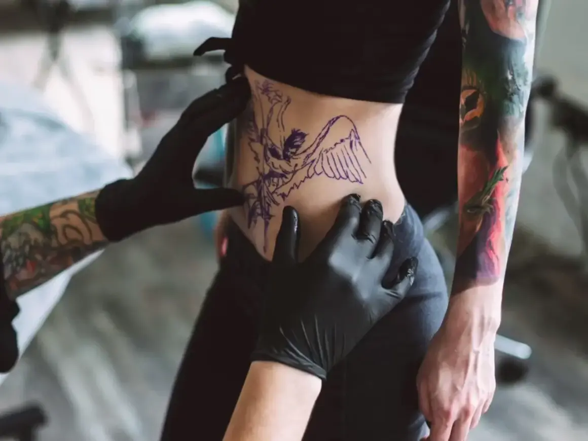 Tätowierer bereitet Motiv vor. Nach dem Stechen ist die Frage: wie lange tattoo mit Bepanthen eincremen?
