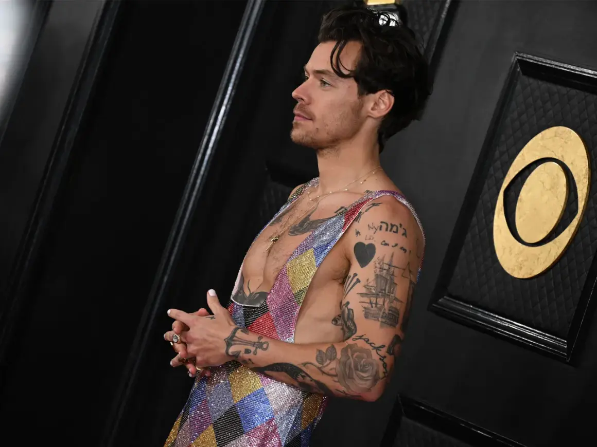Harry Styles mit vielen Tätowierungen, die als Inspiration für Tattoo Ideen Mann dienen. Ein Herz, ein Schiff und Rosen sind zu sehen.
