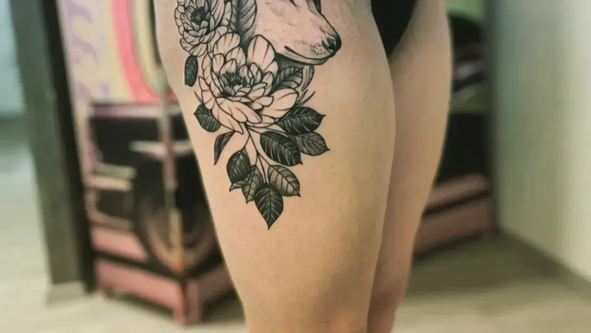 Ein Wolfskopf mit Blumen auf dem Oberschenkel. Die Folie ist ab, bereit für die Heilung.