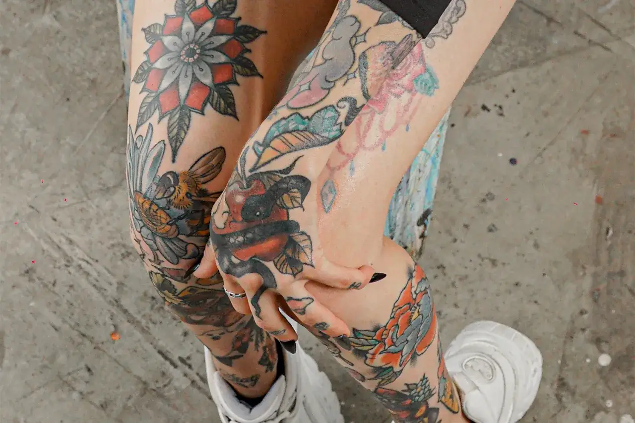 Bunte patchwork tattoo vorlagen zieren Arme und Beine: Blumen, Bienen, Schlangen und Äpfel.