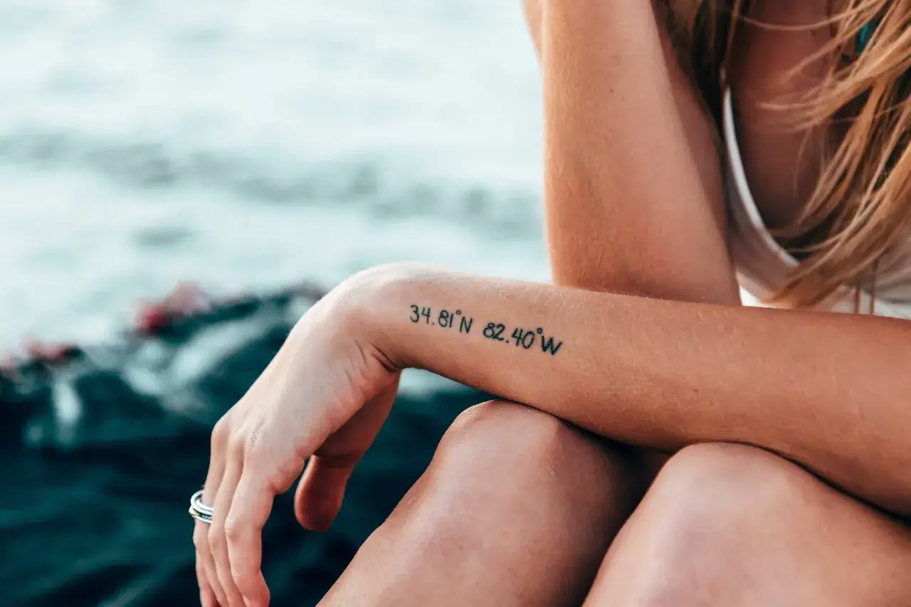 Ein Tattoo mit Koordinaten auf dem Arm, das an den Verlust eines Menschen erinnert. Die Zahlen stehen für einen besonderen Ort.